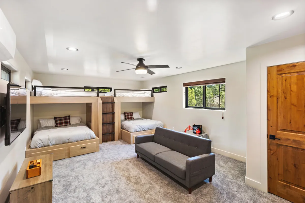 A cozy interior space featuring bunk beds, a sofa, and a wooden storage unit, with natural light streaming through the windows. The setup encourages shared family experiences, like bedtime stories or movie nights, and offers a comfortable retreat after a day outside.